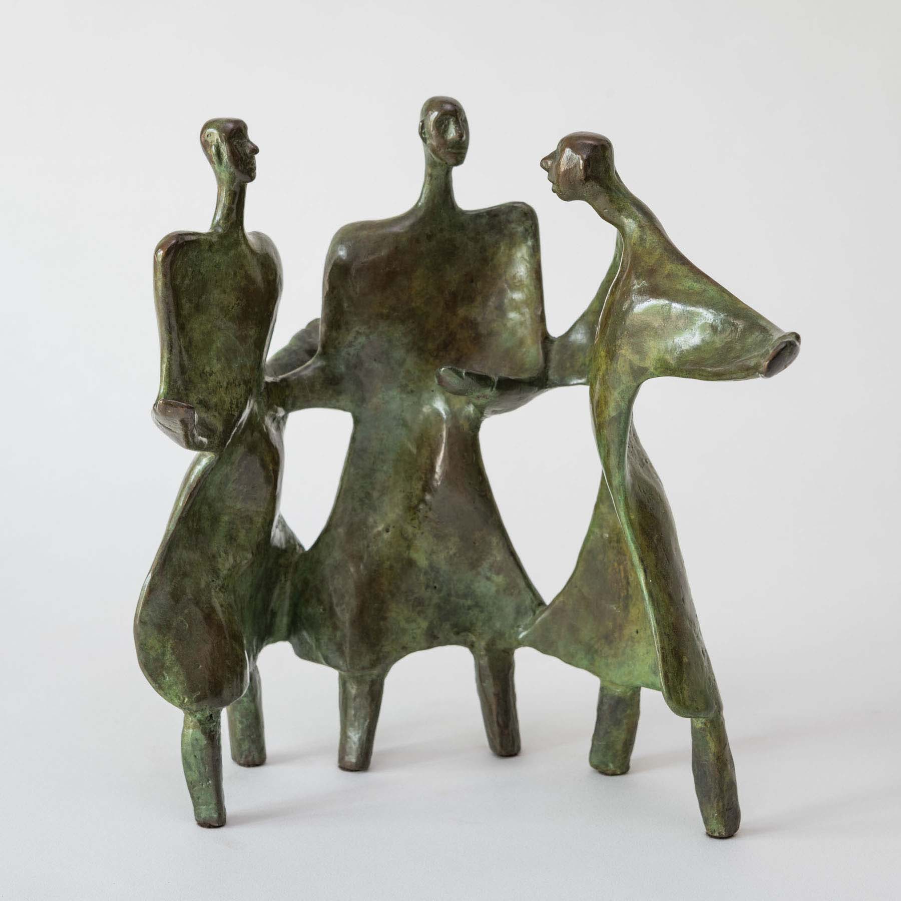 A bronze sculpture of three, abstract human figures all connected and standing in a semi-circle.