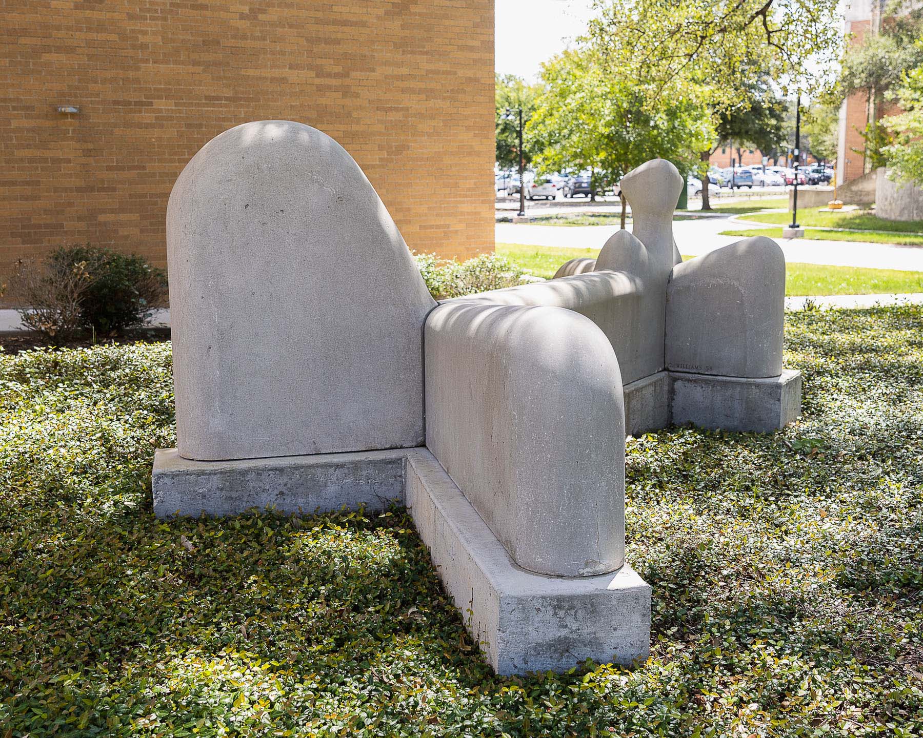 A large, white figural sculpture in a reclining position in an outdoor setting.