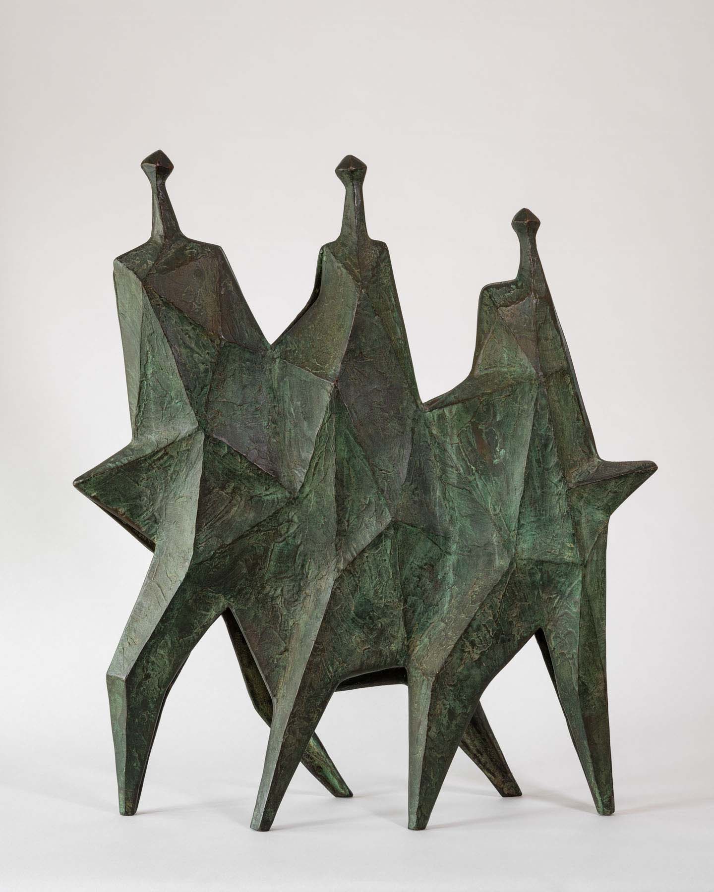 Bronze sculpture of three human-like geometric figures that are attached in the center.