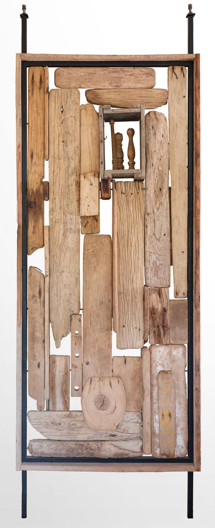 Pieces of flat, worn wood of different sizes and shapes assembled in a metal frame.