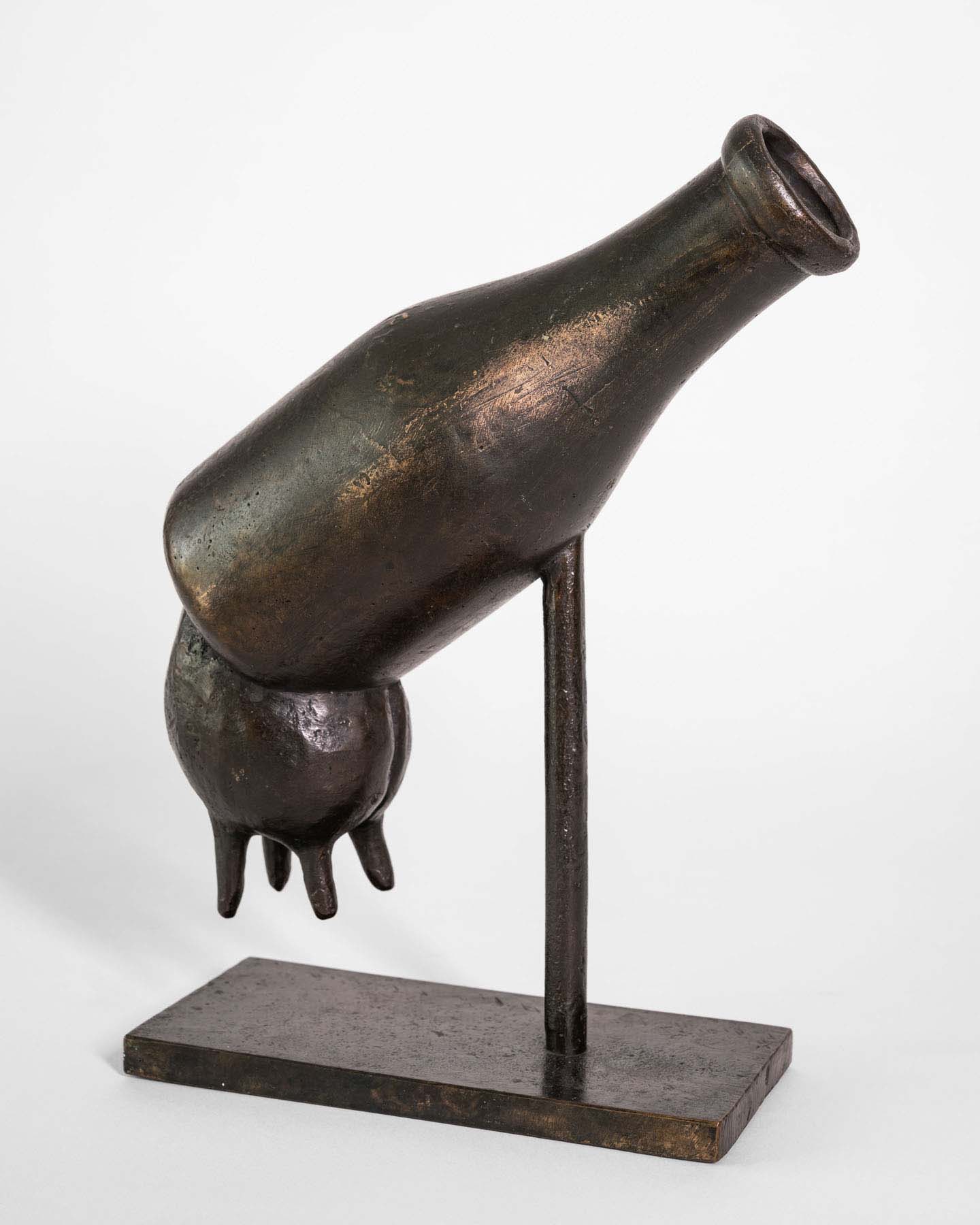 Bronze sculpture of a milk bottle with a cow udder hanging off the bottom.