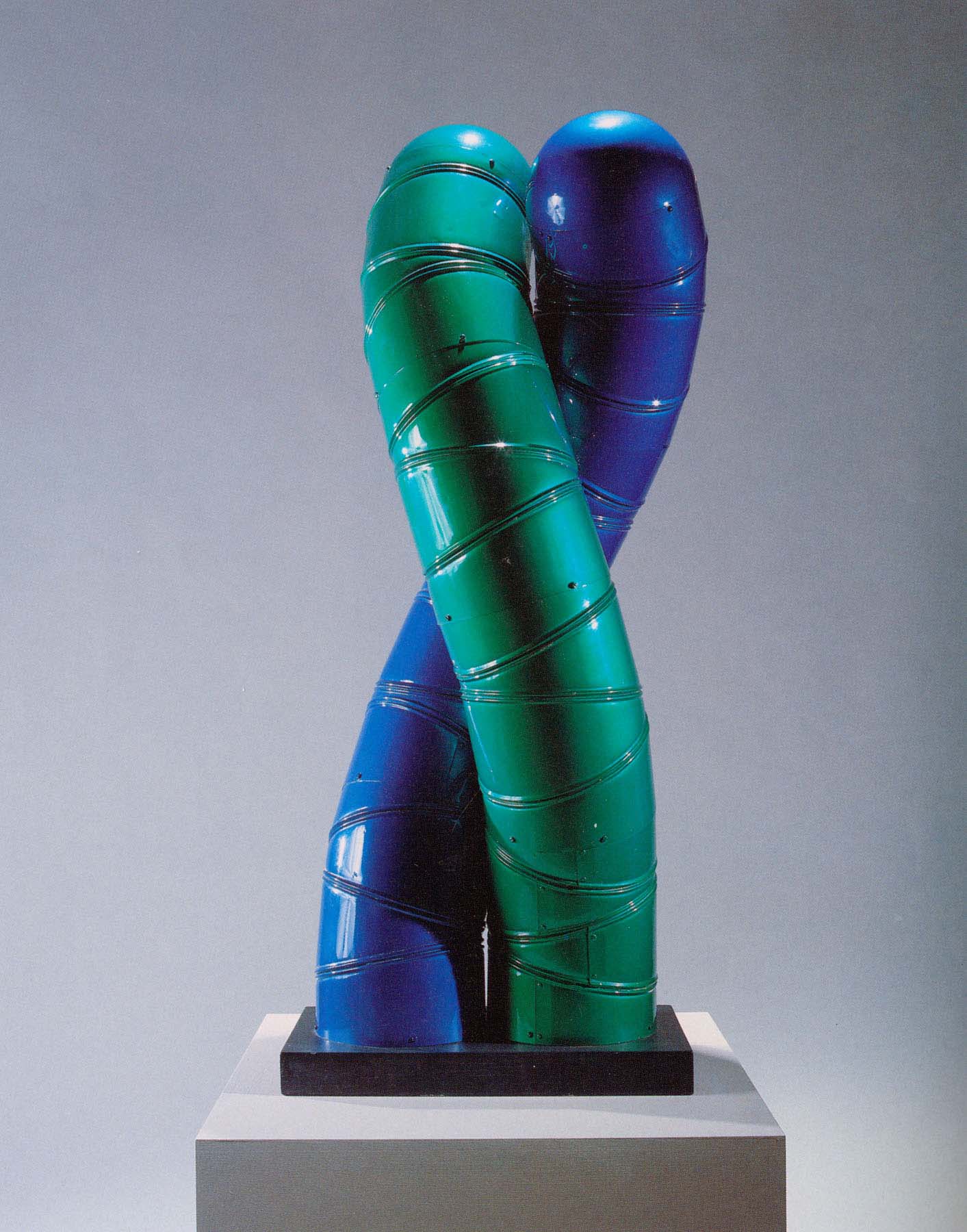 Sculpture of one blue and one green tube that extend upright and twist closely around each other.