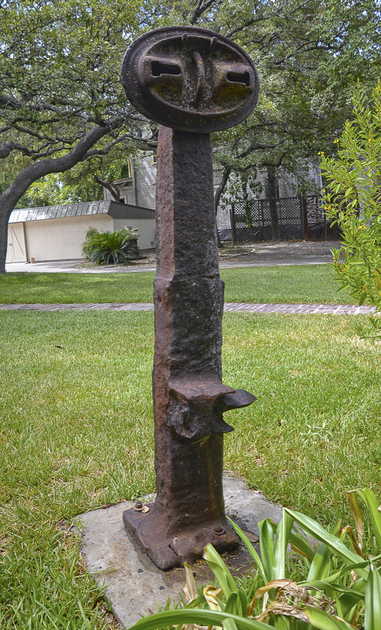 Tall, metal, outdoor sculpture with an oval disk at the top.