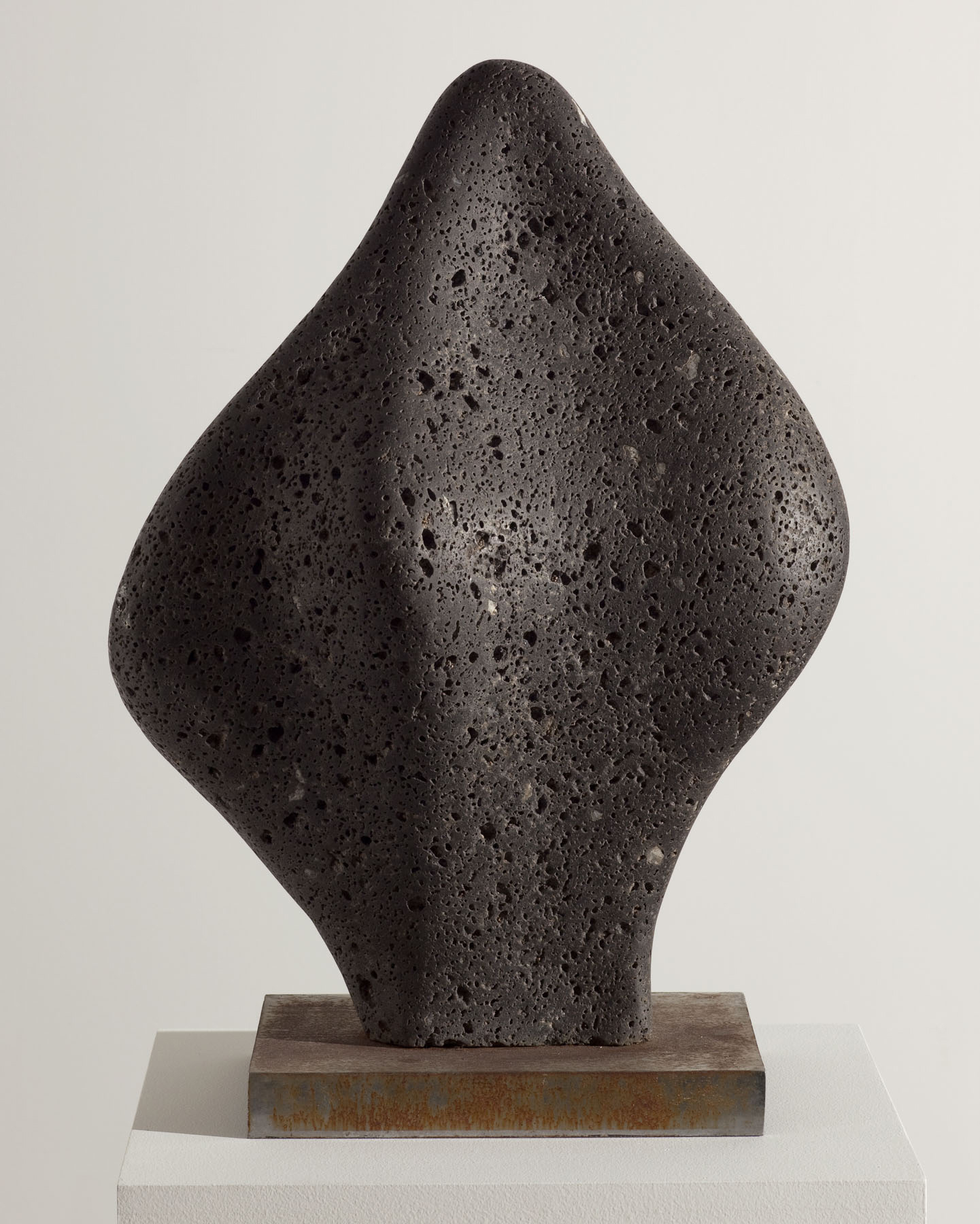 Organically-shaped black stone sculpture with a porous surface.