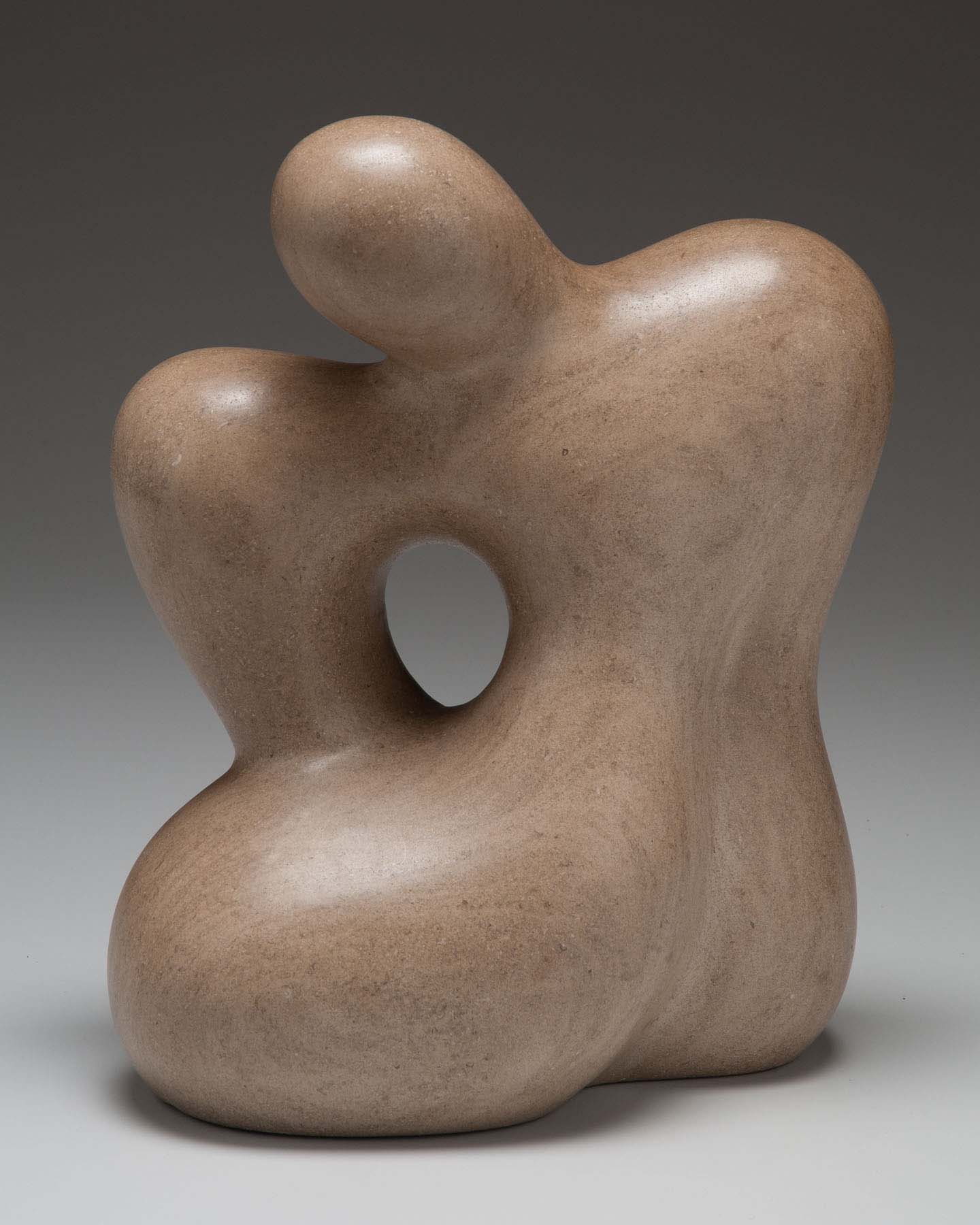 A smooth stone sculpture of an abstract, bulbous seated figure.